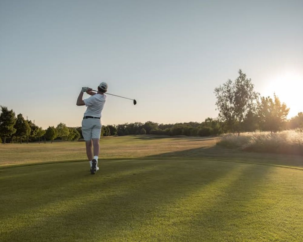 Golfer swinging on fairway course